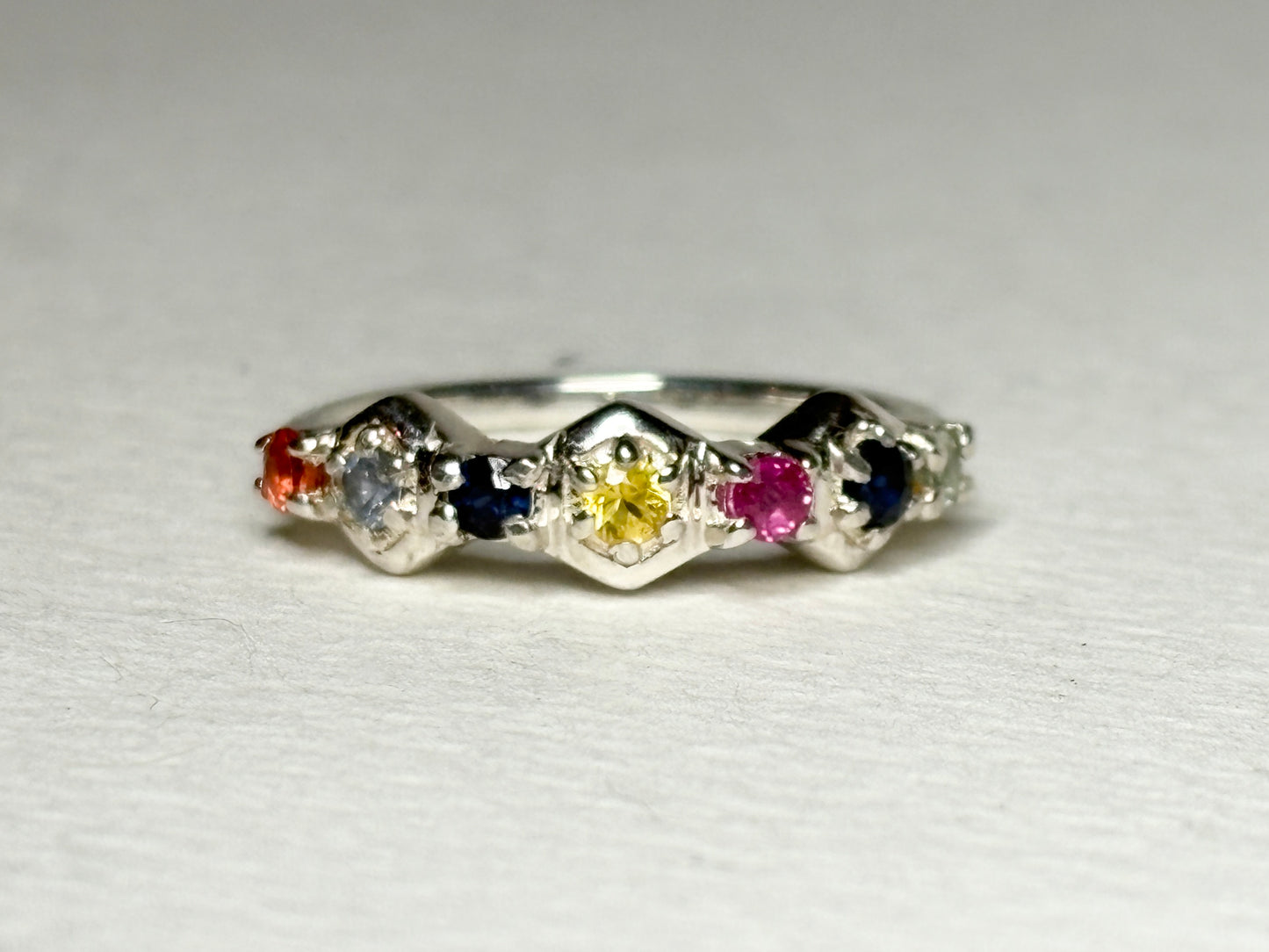 Sterling silver band ring with honeycomb shapes and multi-colored sapphires and ruby.