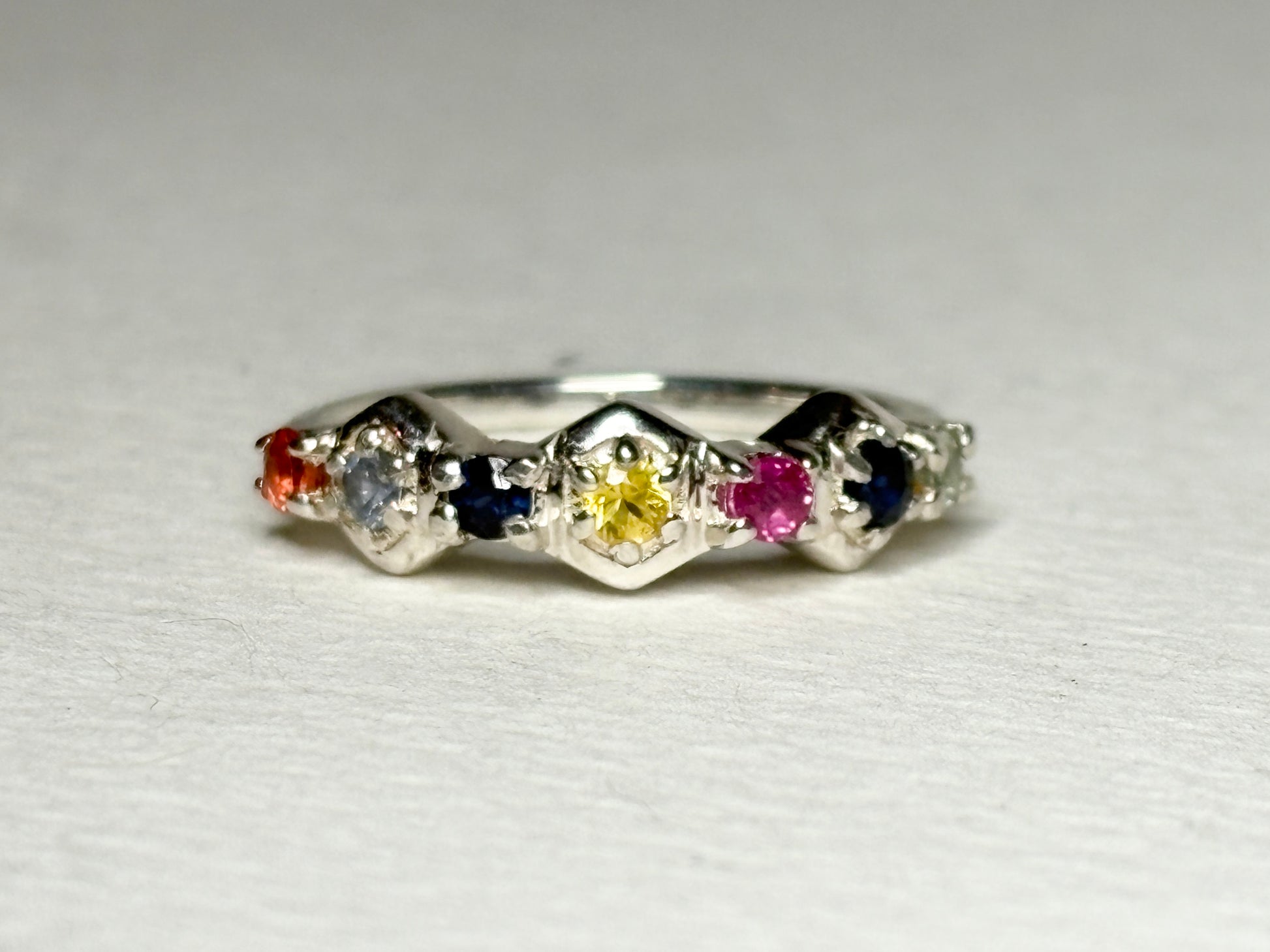 Sterling silver band ring with honeycomb shapes and multi-colored sapphires and ruby.