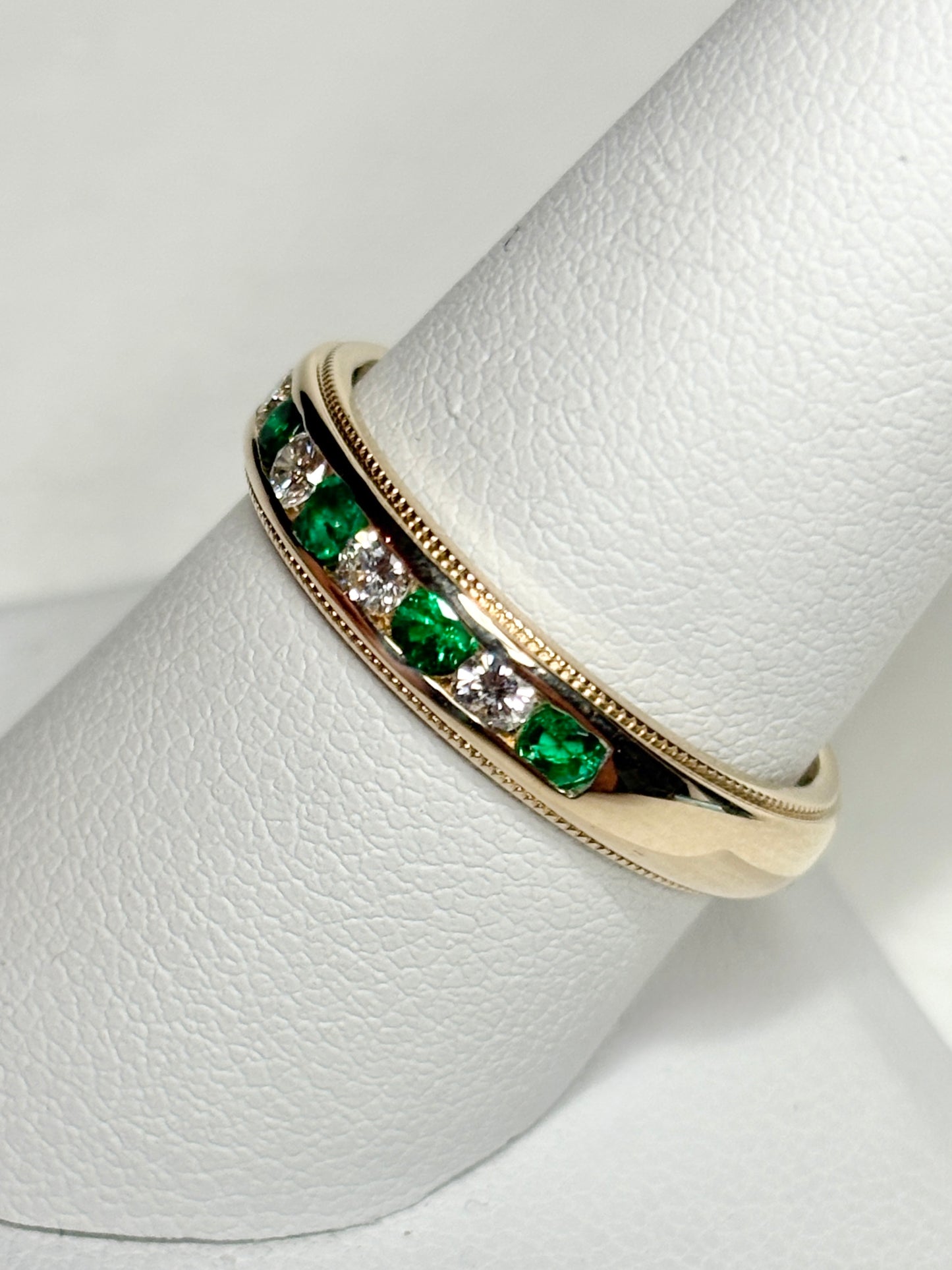 18k gold band ring with alternating emeralds and diamonds.