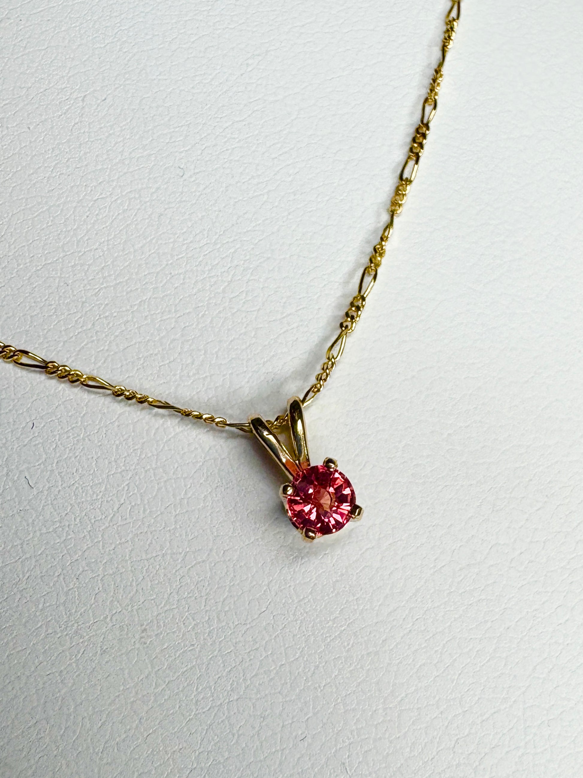 Small 14k gold necklace with a round pink sapphire pendant.