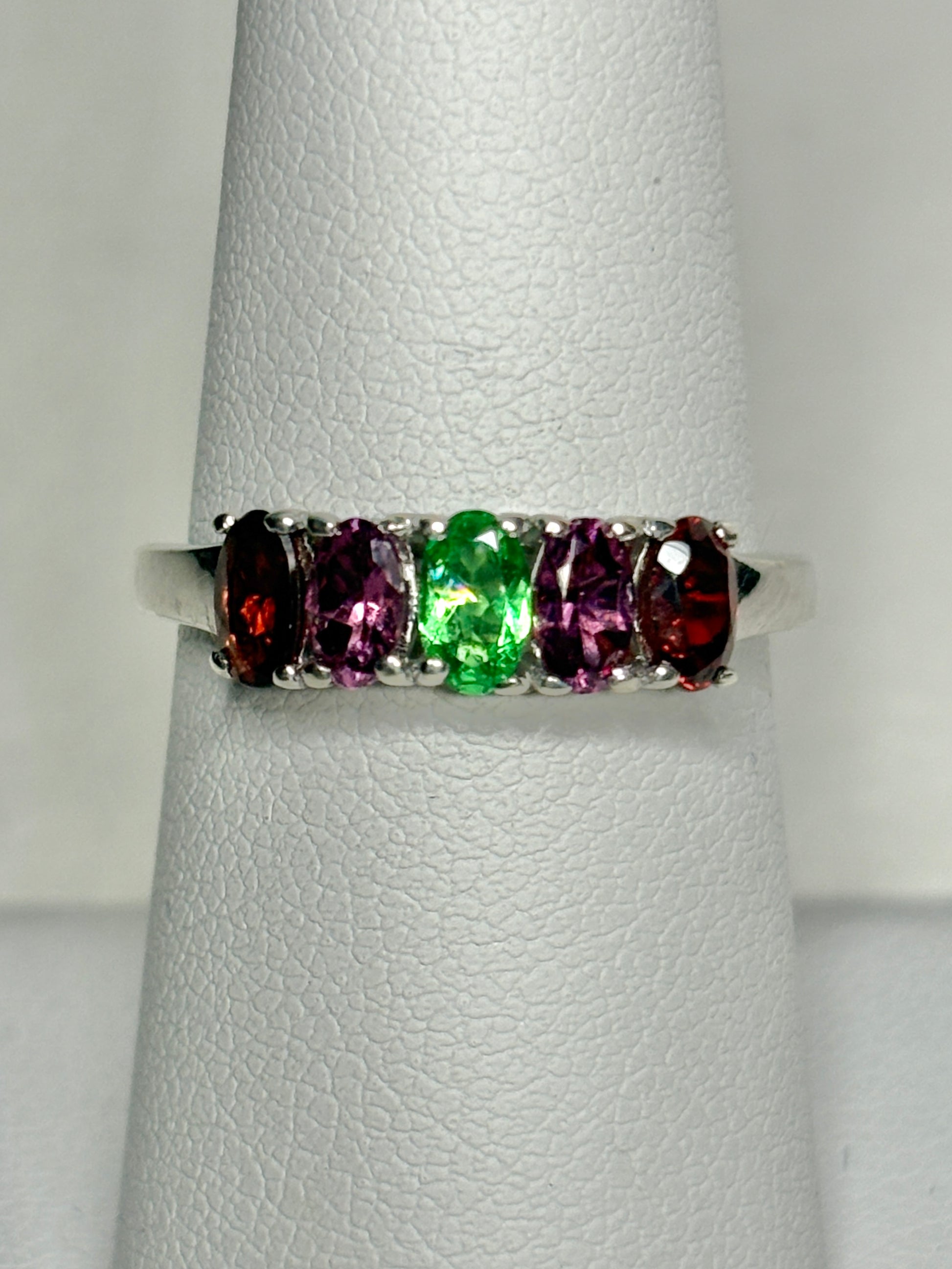 Sterling silver band ring with five oval garnets in red, pink, and green.