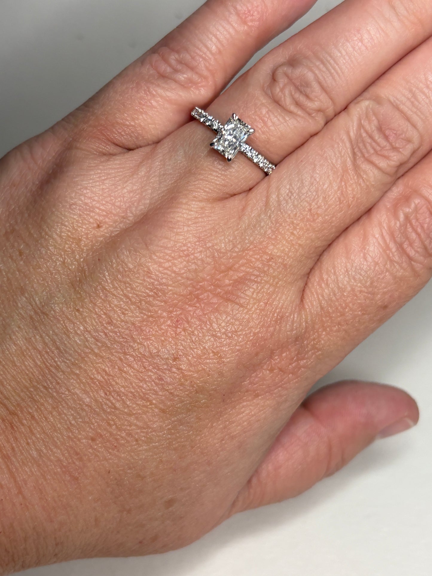 A 14k white gold engagement ring with a rectangular diamond and accent stones.