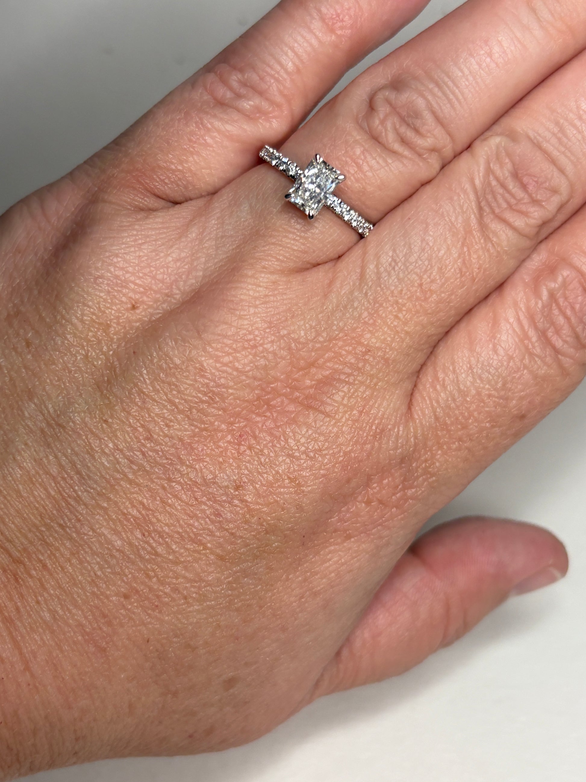 A 14k white gold engagement ring with a rectangular diamond and accent stones.