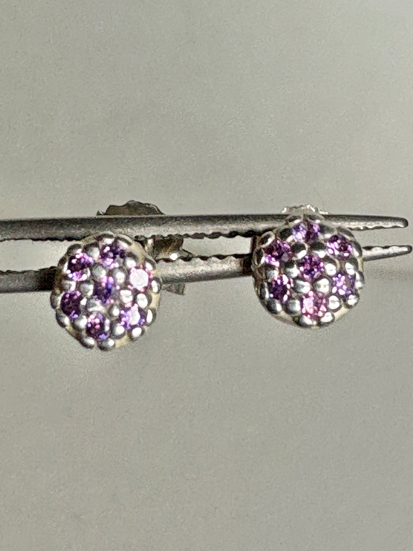 Sterling silver stud earrings with pave-set violet purple cubic zirconia stones.