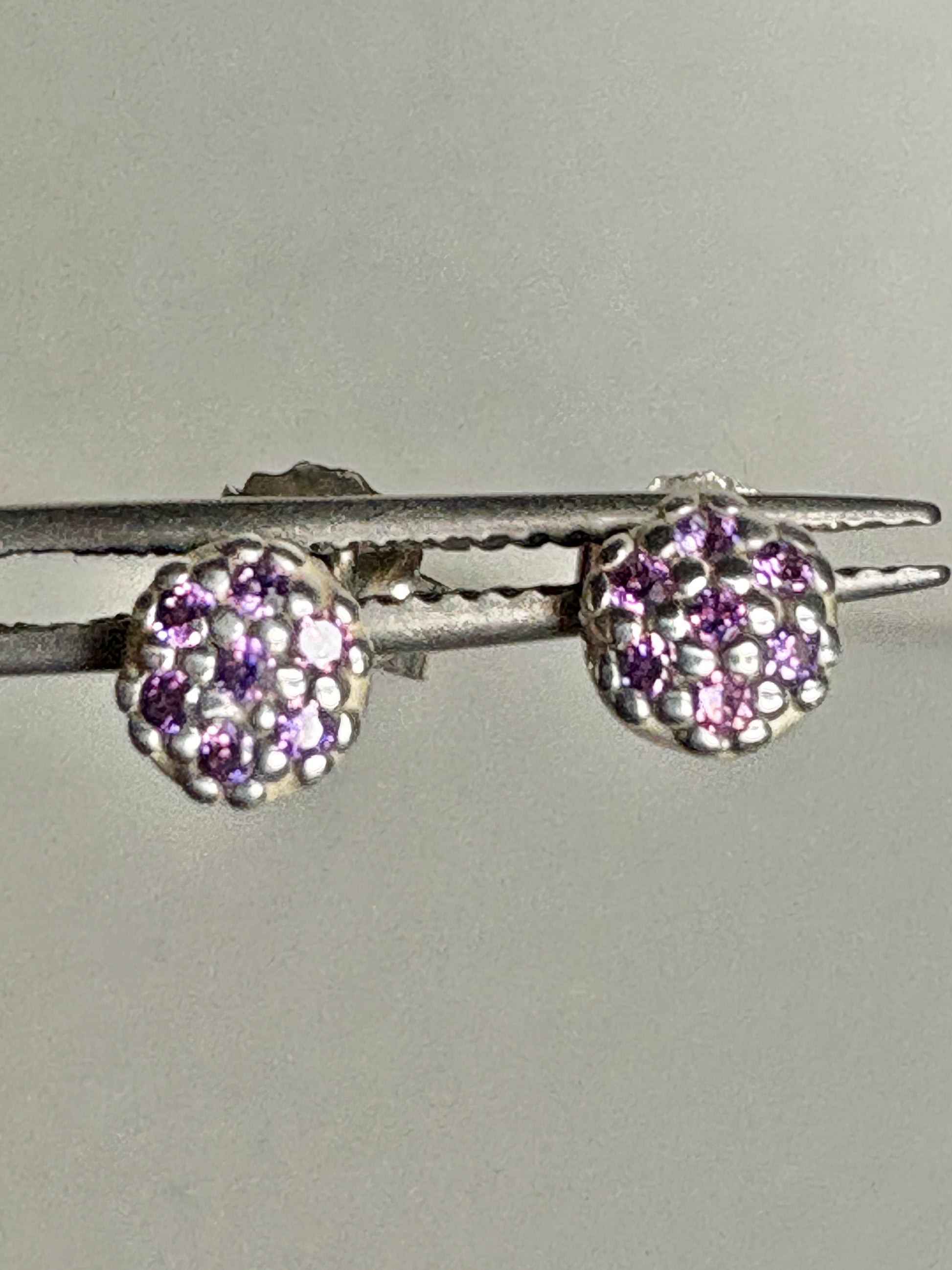 Sterling silver stud earrings with pave-set violet purple cubic zirconia stones.