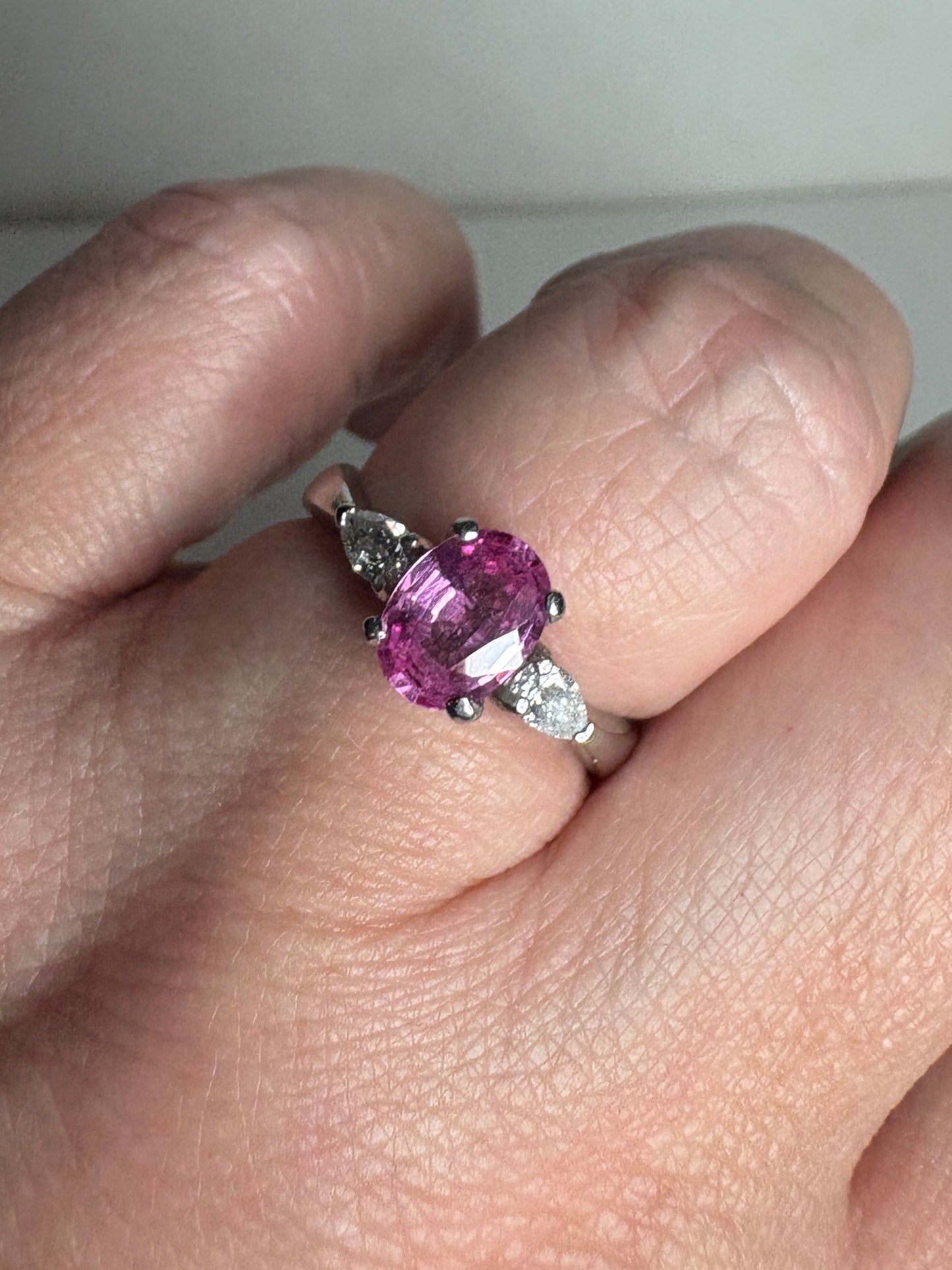 Platinum ring with oval pink sapphire and pear-shaped diamonds.