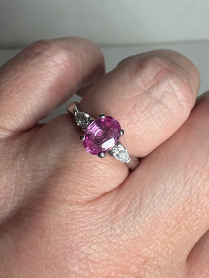 Platinum ring with oval pink sapphire and pear-shaped diamonds.