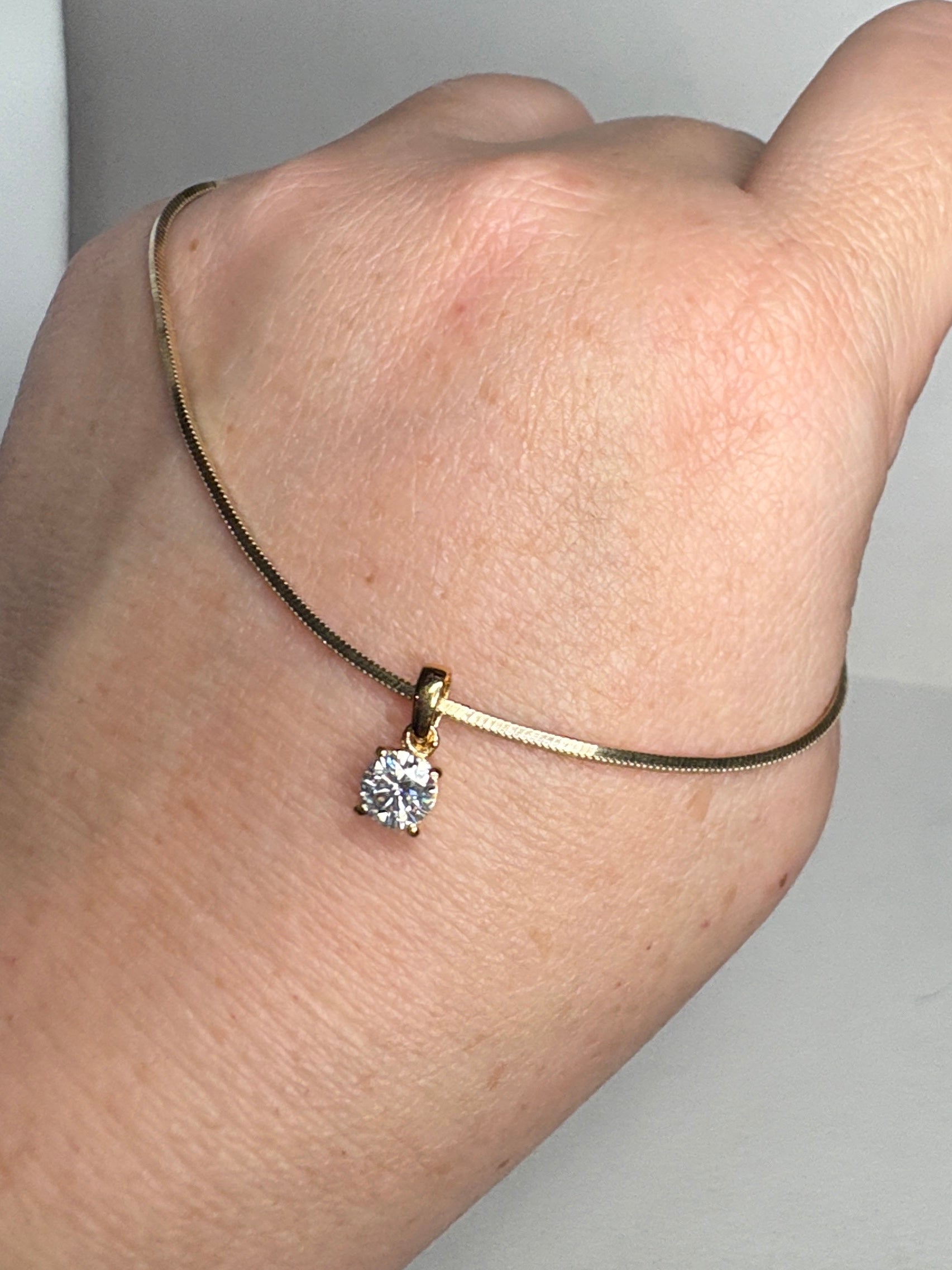 Gold over sterling silver snake chain necklace with a moissanite solitaire pendant.