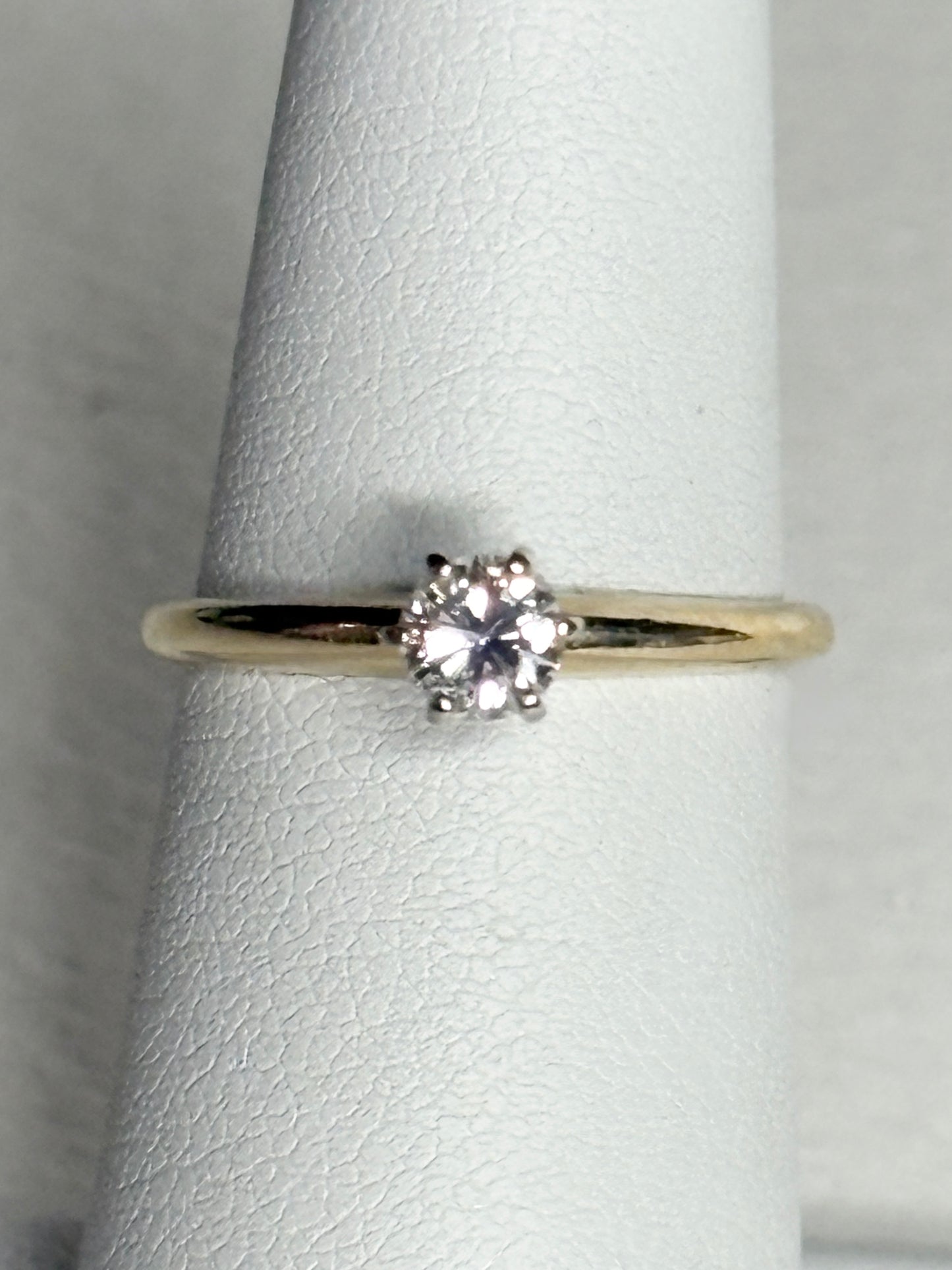 A 14k gold ring with a 0.28ct diamond set in white gold prongs.