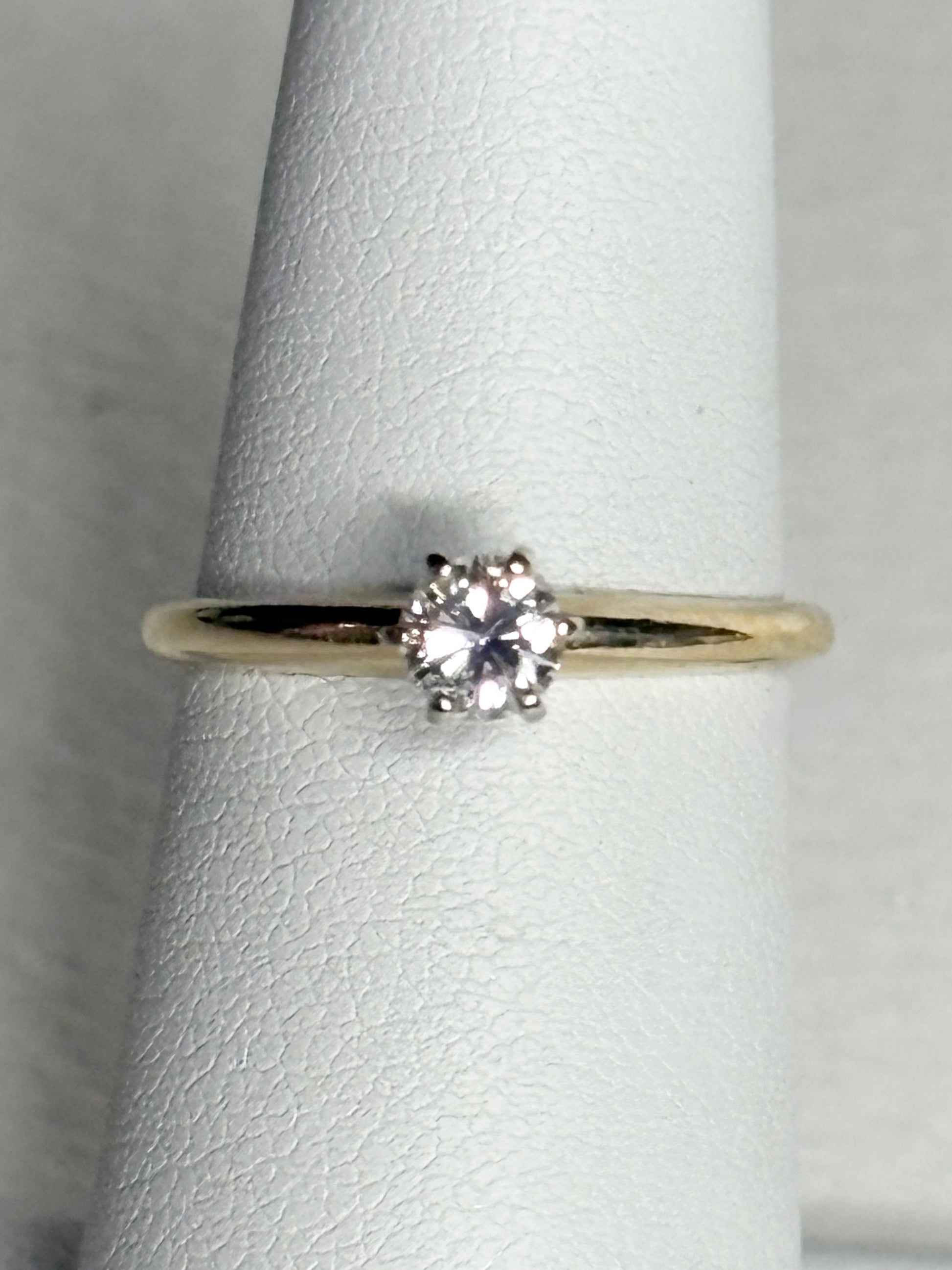 A 14k gold ring with a 0.28ct diamond set in white gold prongs.