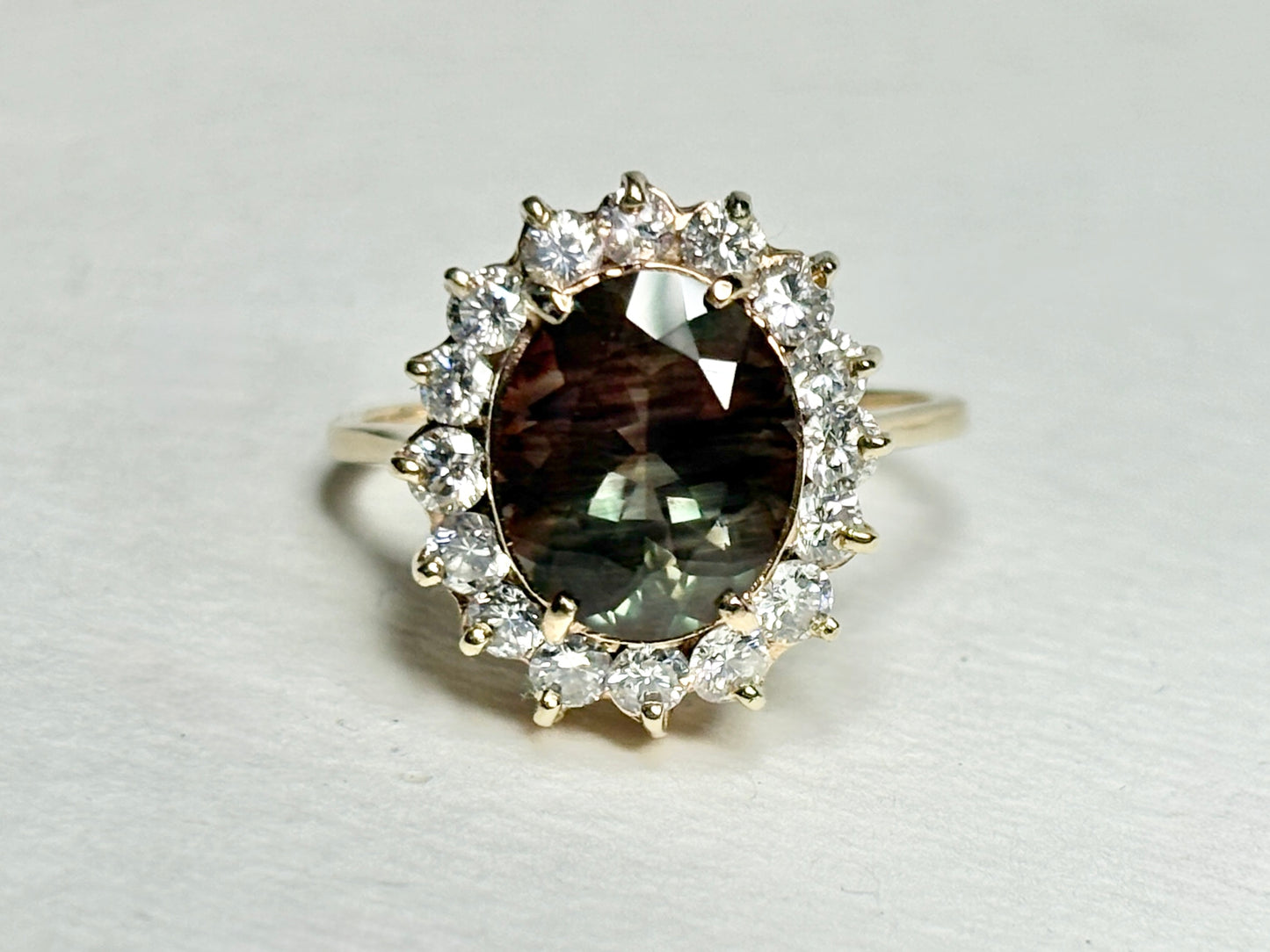 Oval dichroic Oregon sunstone ring with diamond halo in 14k gold.