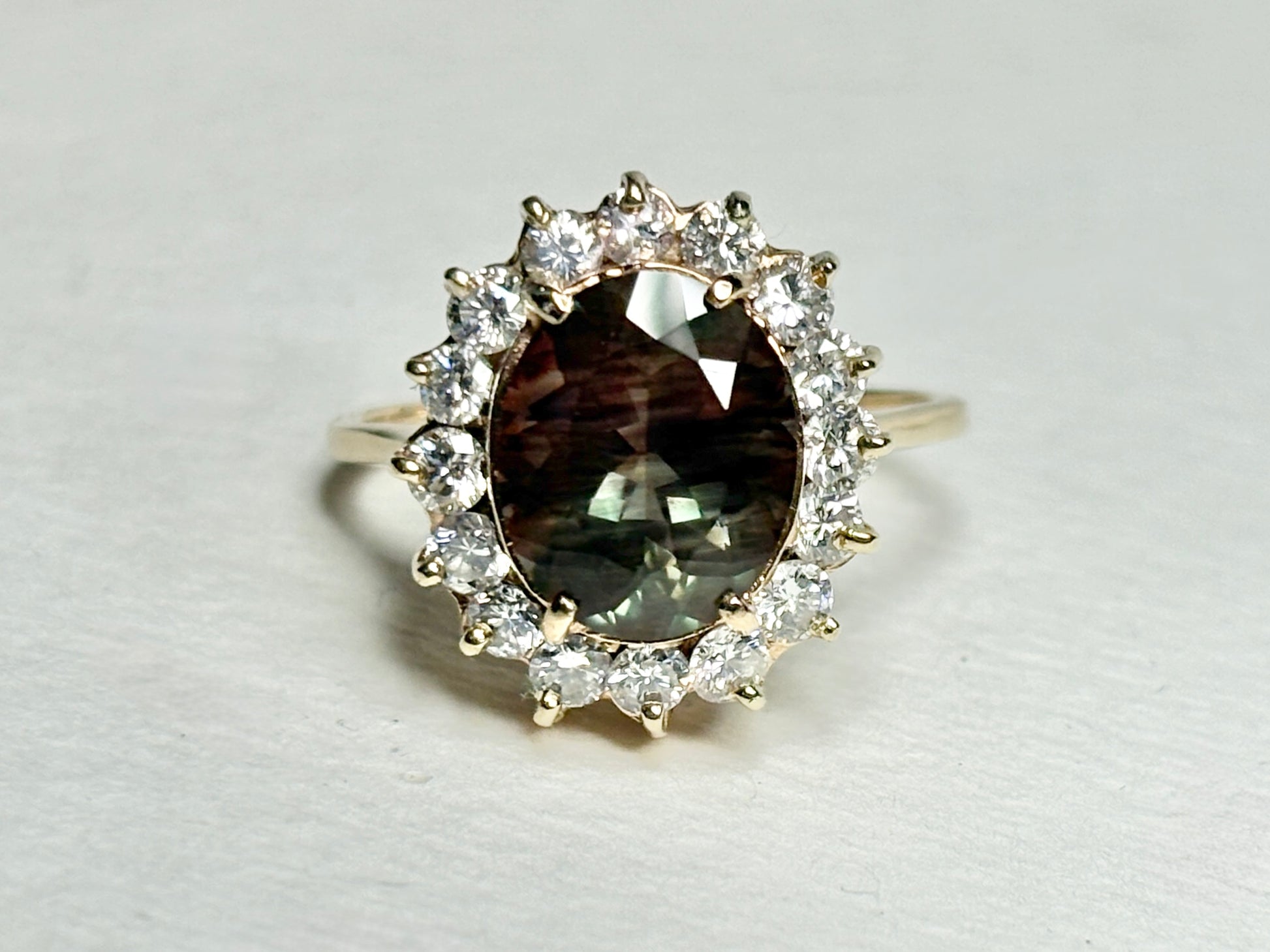 Oval dichroic Oregon sunstone ring with diamond halo in 14k gold.