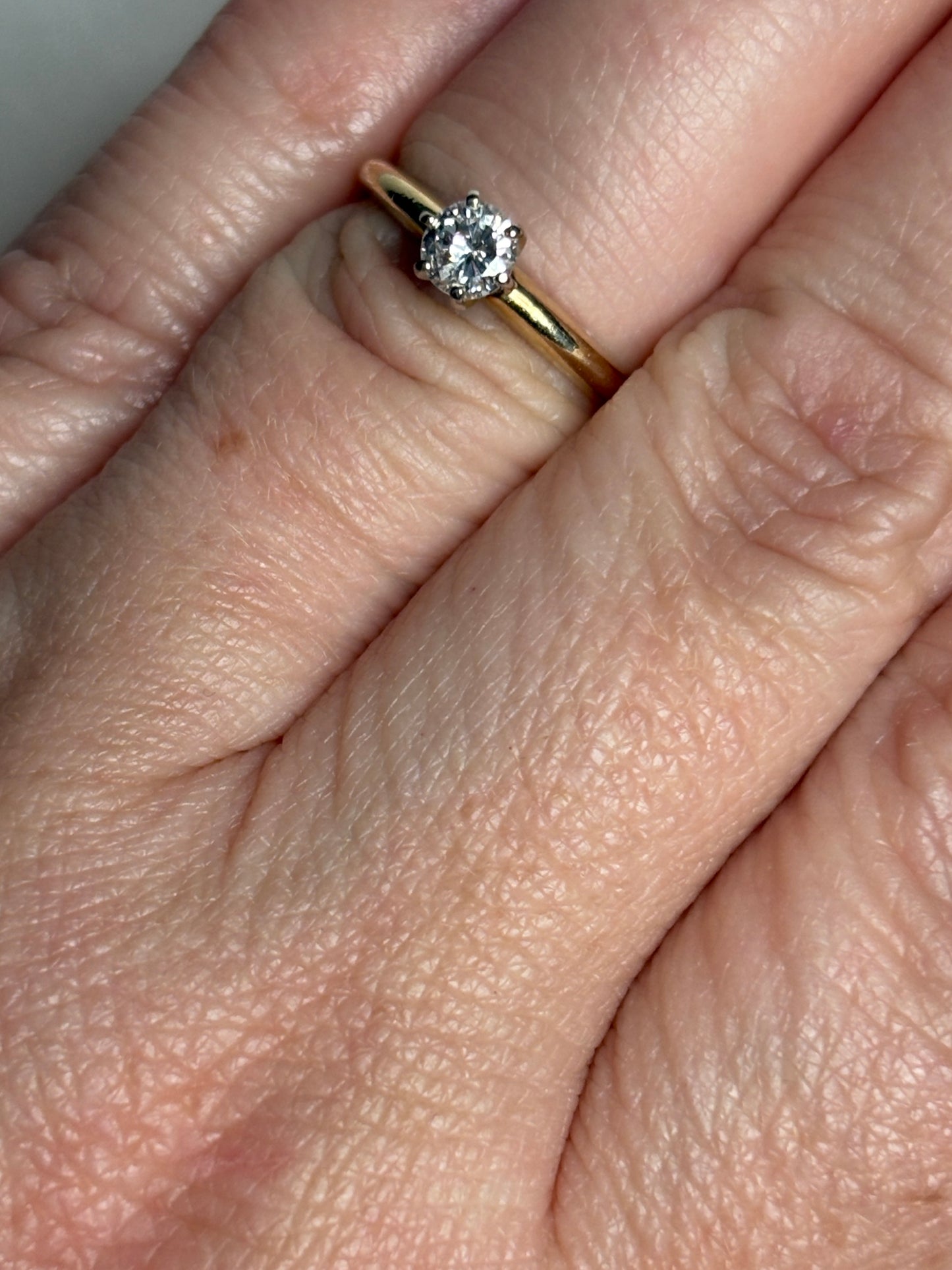 A 14k gold ring with a 0.28ct diamond set in white gold prongs.