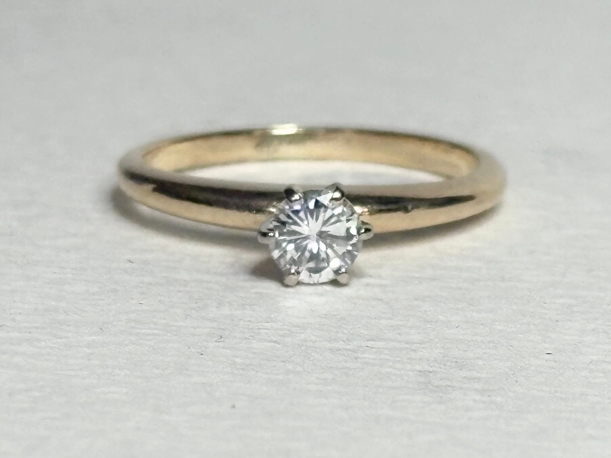 A 14k gold ring with a single diamond set in six prongs.