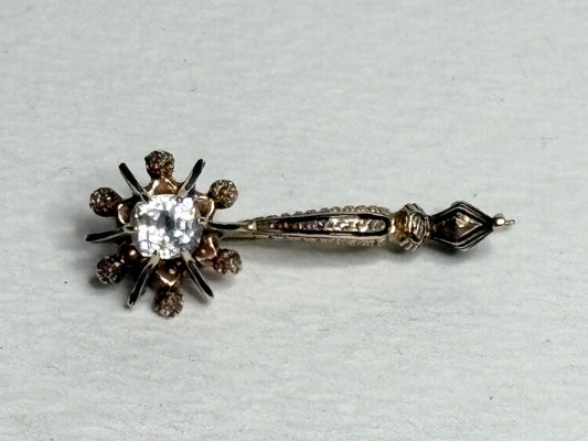 Antique 14k gold brooch pin with a central paste gem and enamel detailing.