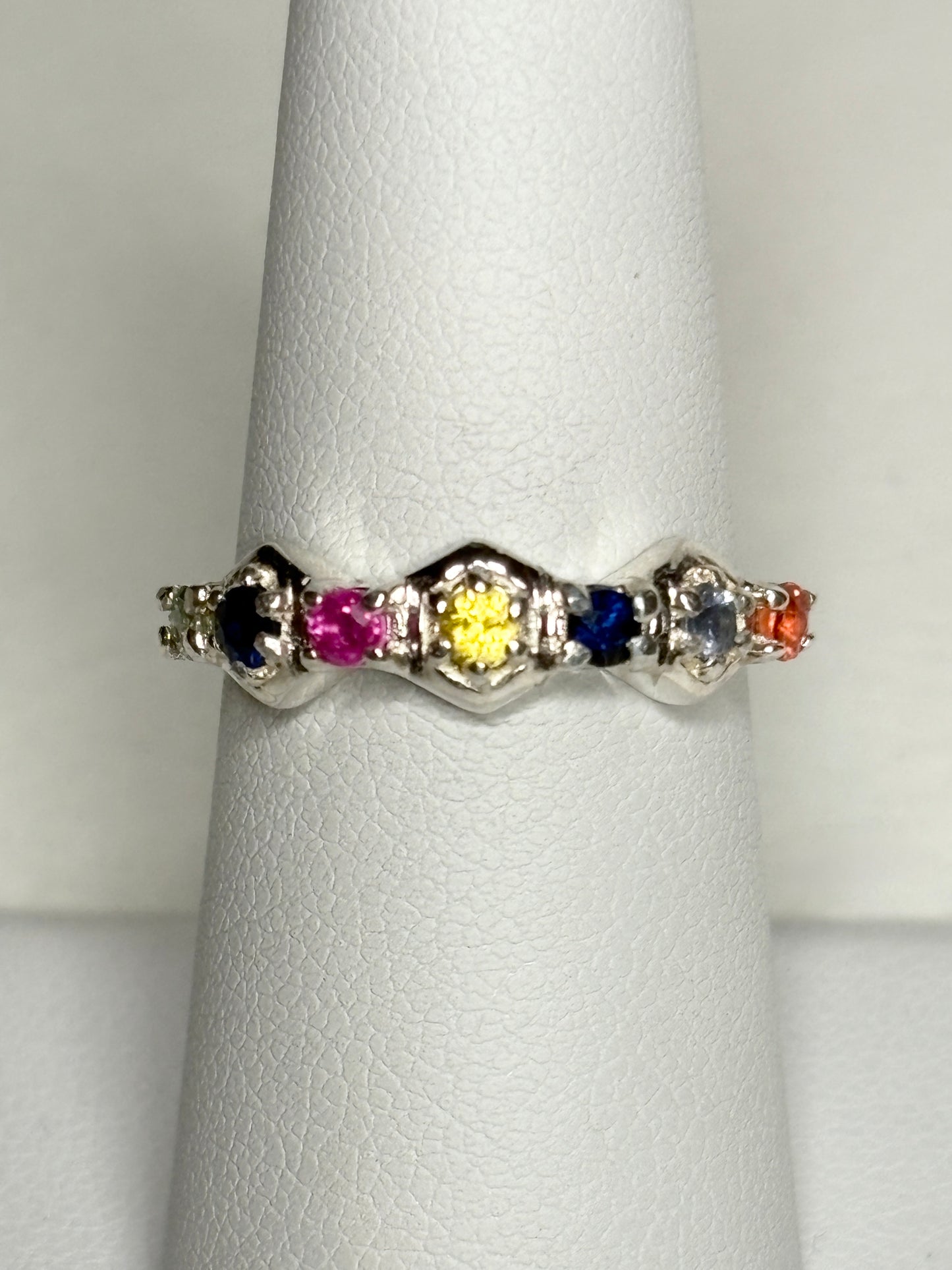 Sterling silver band ring with honeycomb shapes and multi-colored sapphires and ruby.