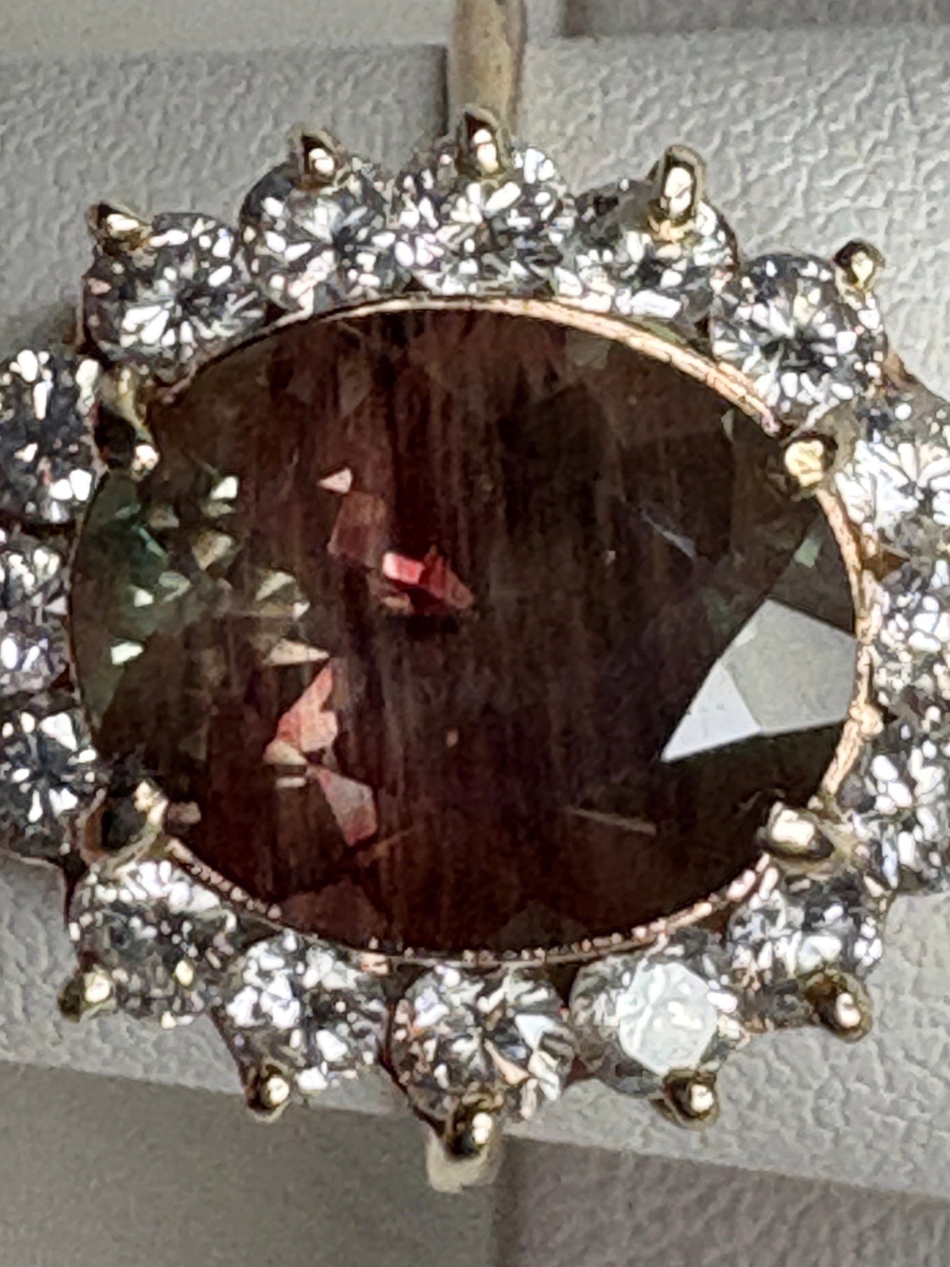 Oval dichroic Oregon sunstone ring with diamond halo in 14k gold.