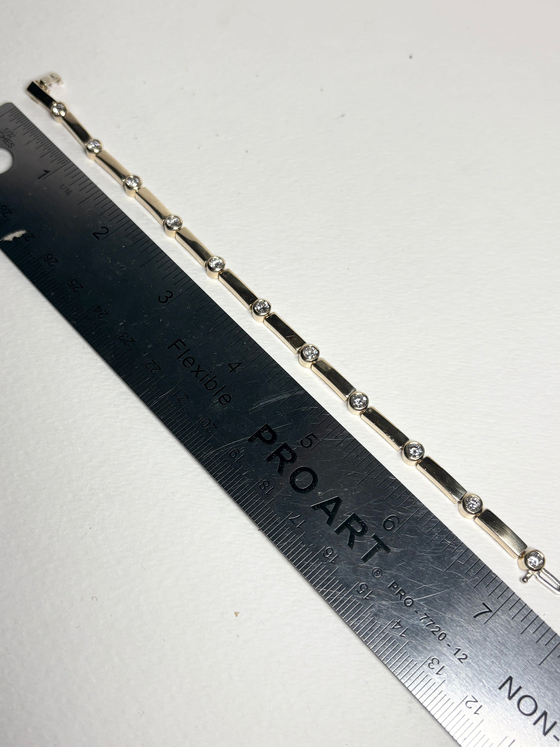 14k yellow gold tennis bracelet with 11 bezel-set diamonds, 7.25 inches long.