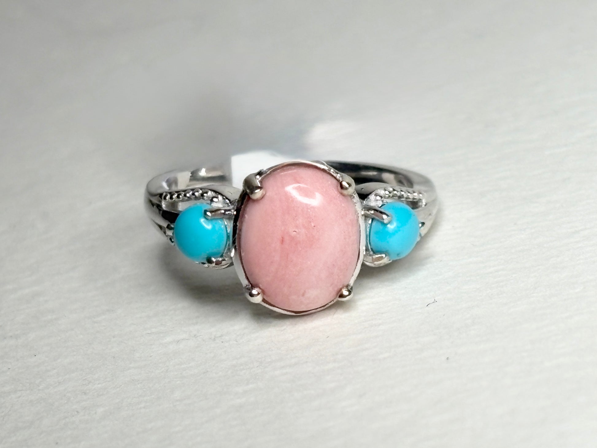 Sterling silver ring with oval peach opal and two round turquoise cabochons.