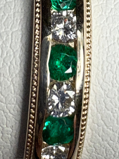 18k gold band ring with alternating emeralds and diamonds, featuring milgrain detail.