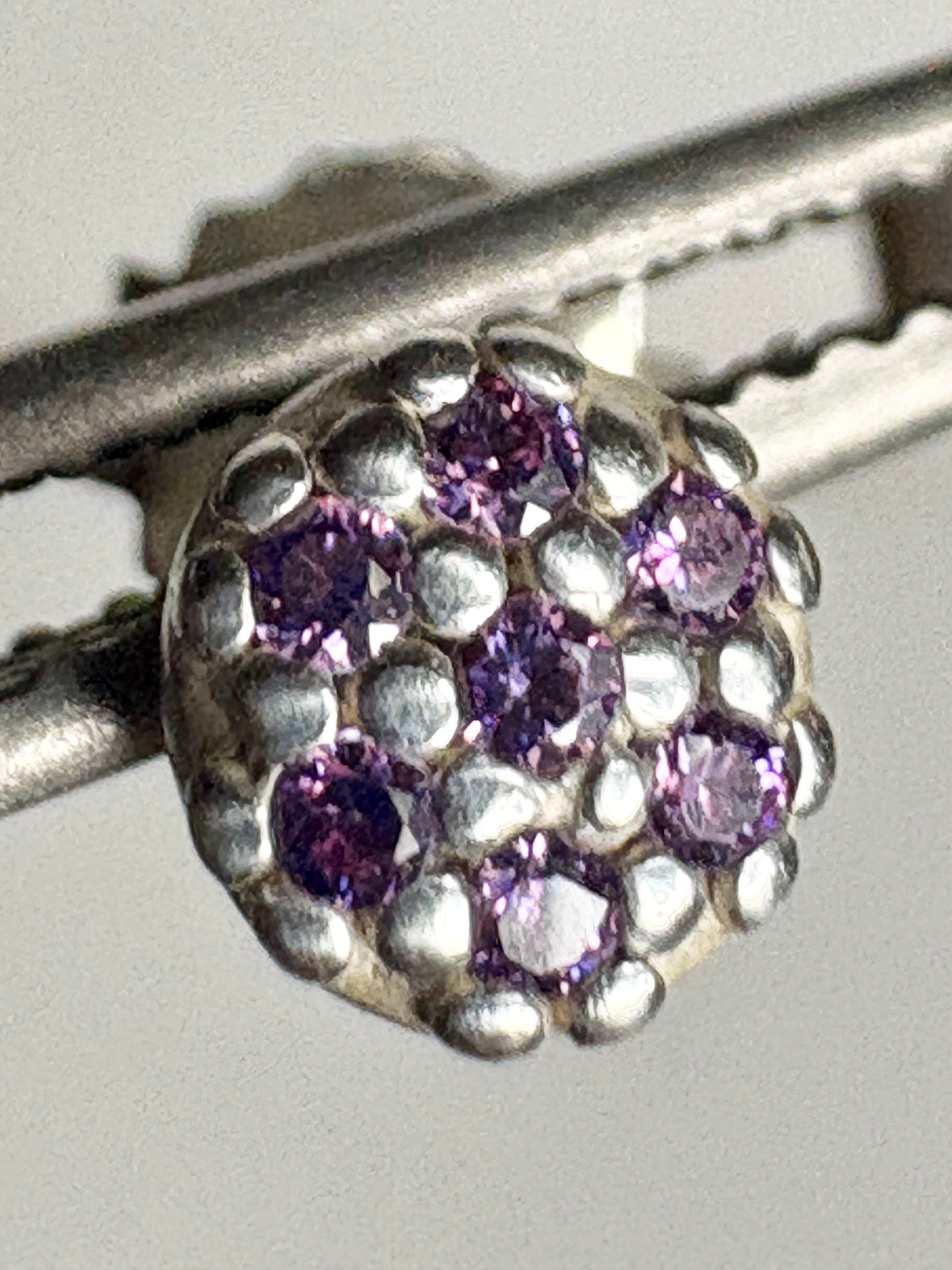 Sterling silver stud earrings with pave-set violet cubic zirconia stones.