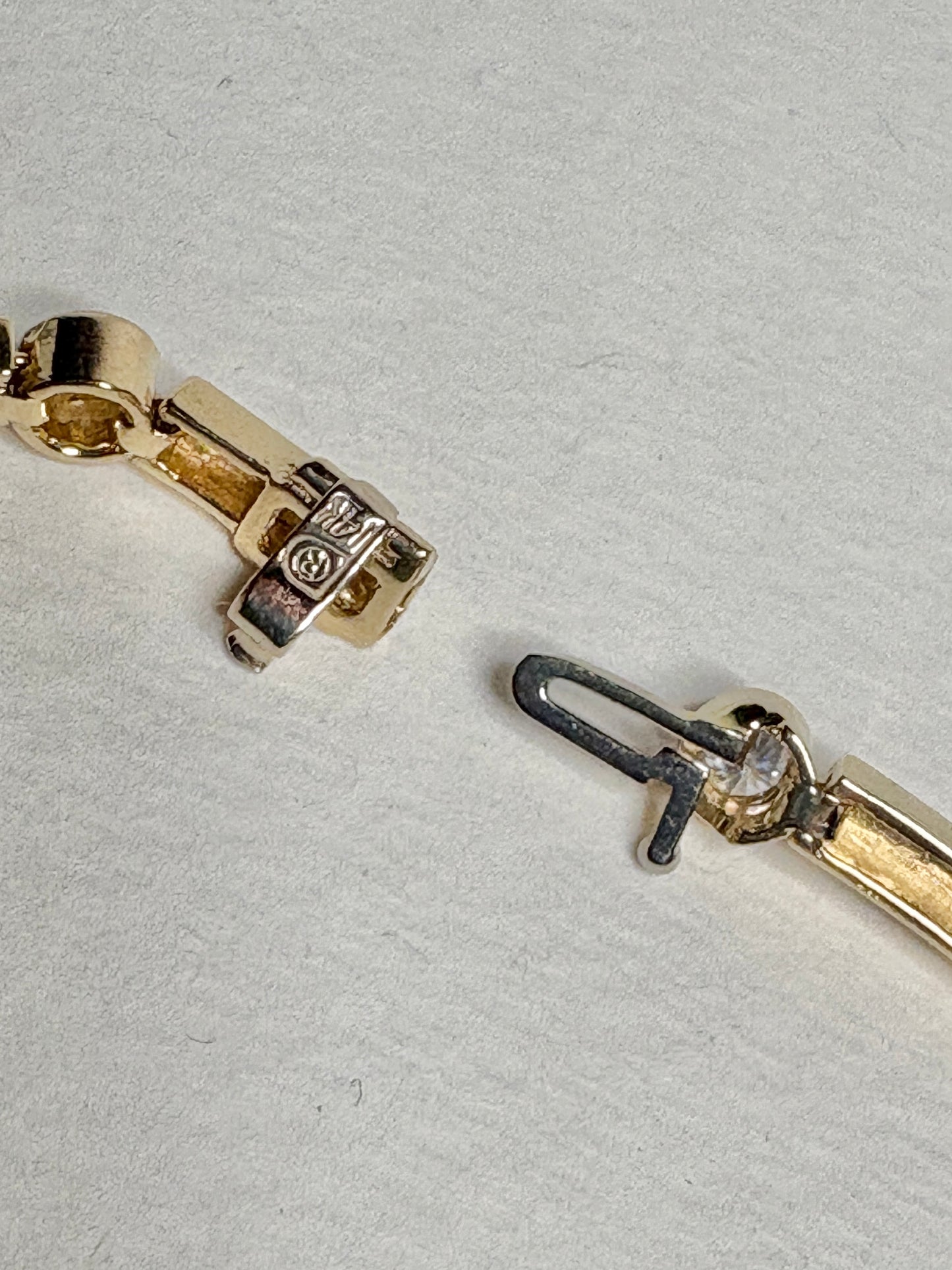 A 14k gold tennis bracelet with bezel-set diamonds.