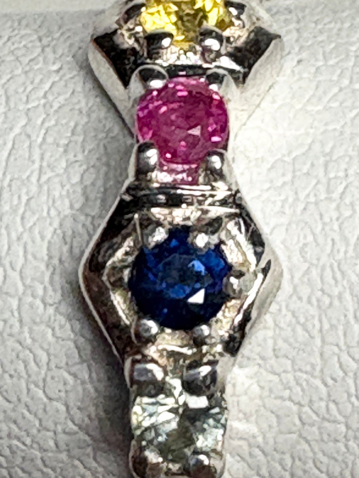 Sterling silver band ring with a ruby, blue sapphire, and yellow sapphire.