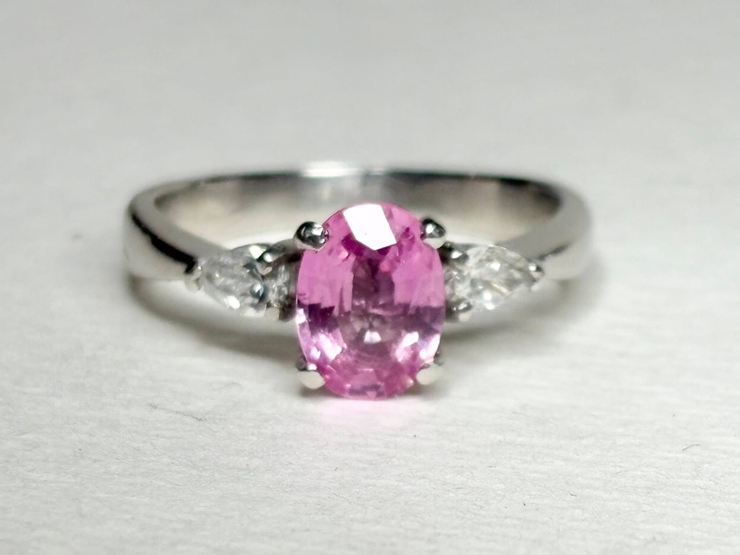 Platinum ring with oval pink sapphire and pear-shaped diamonds.