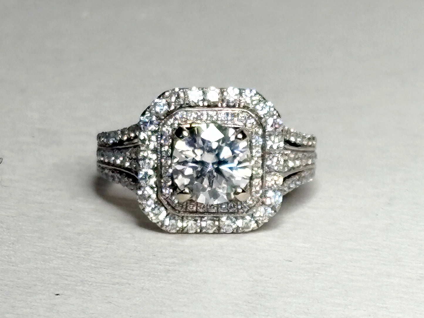 A 14k white gold ring with a central moissanite and a double halo of diamonds.