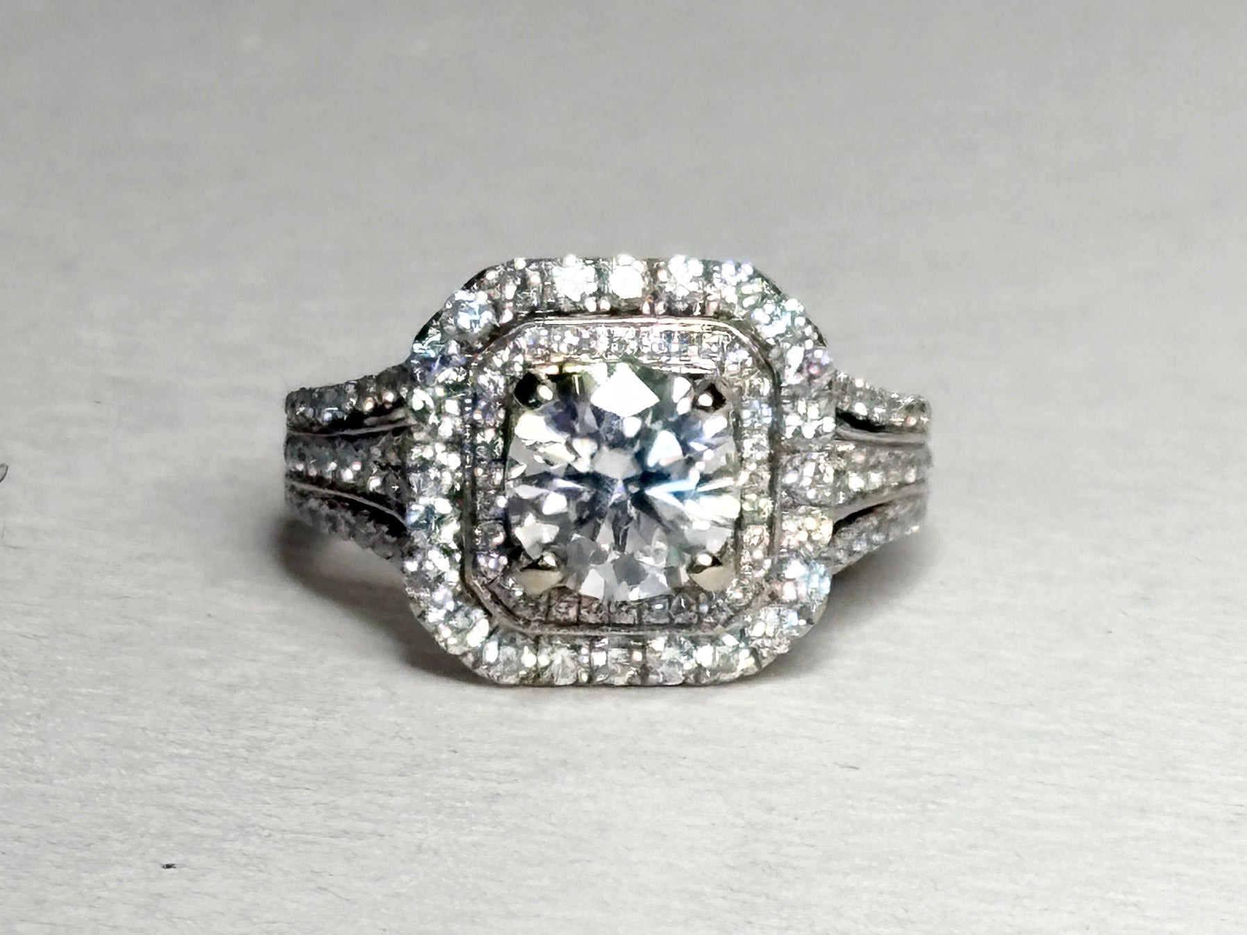 A 14k white gold ring with a central moissanite and a double halo of diamonds.