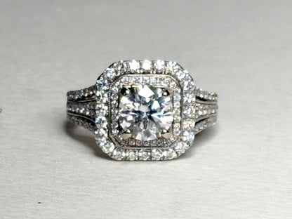 A 14k white gold ring with a central moissanite and a double halo of diamonds.