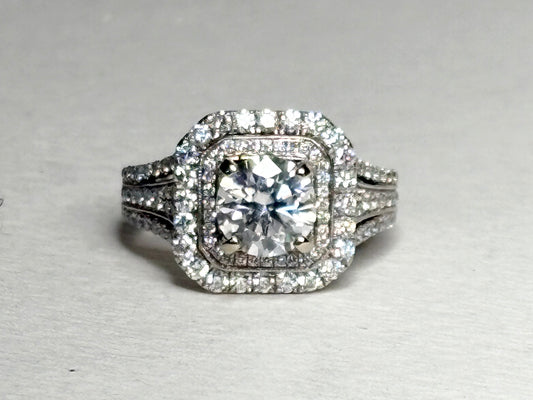 A 14k white gold ring with a central moissanite and a double halo of diamonds.
