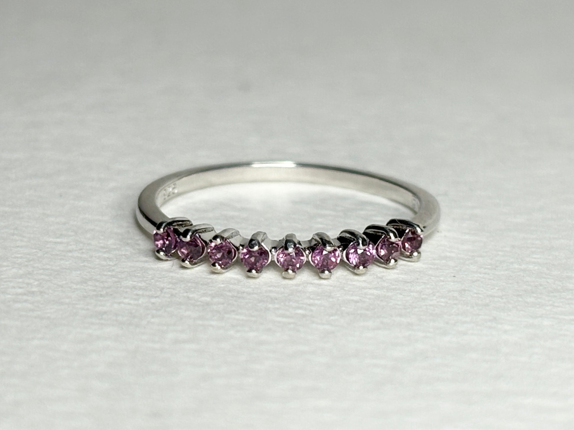Sterling silver band ring with eight small pink rhodolite garnets.
