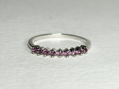 Sterling silver band ring with eight small pink rhodolite garnets.