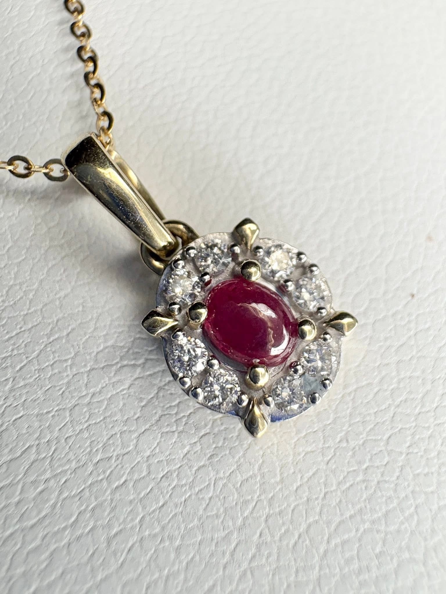 Oval ruby pendant with diamond halo on a gold chain.