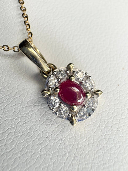 Oval ruby pendant with diamond halo on a gold chain.