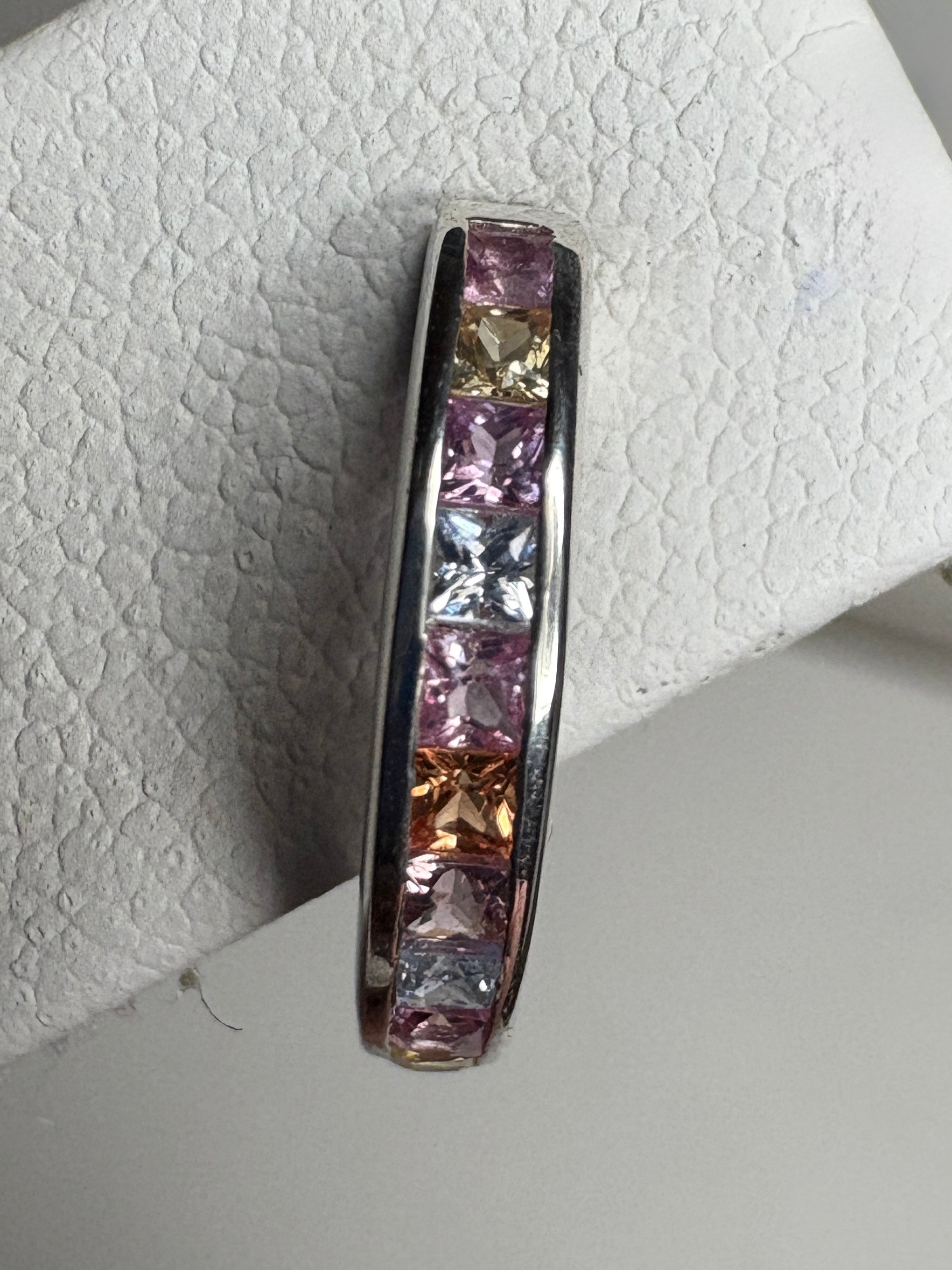Sterling silver huggie hoop earrings with channel-set princess-cut multi-color sapphires.