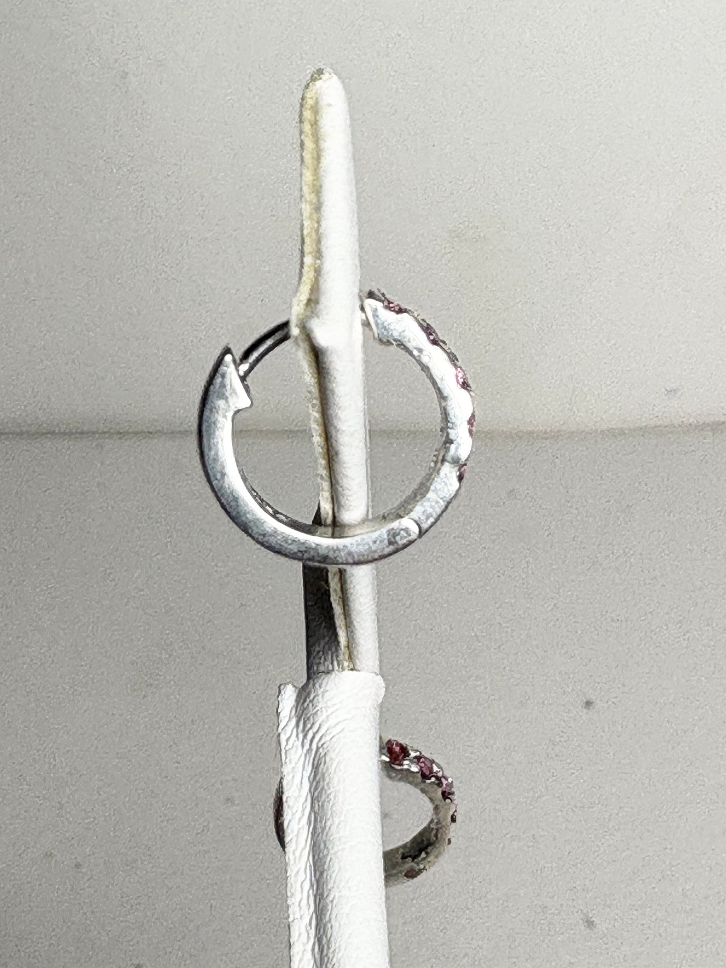 Small sterling silver huggie hoop earrings with rhodolite garnets.