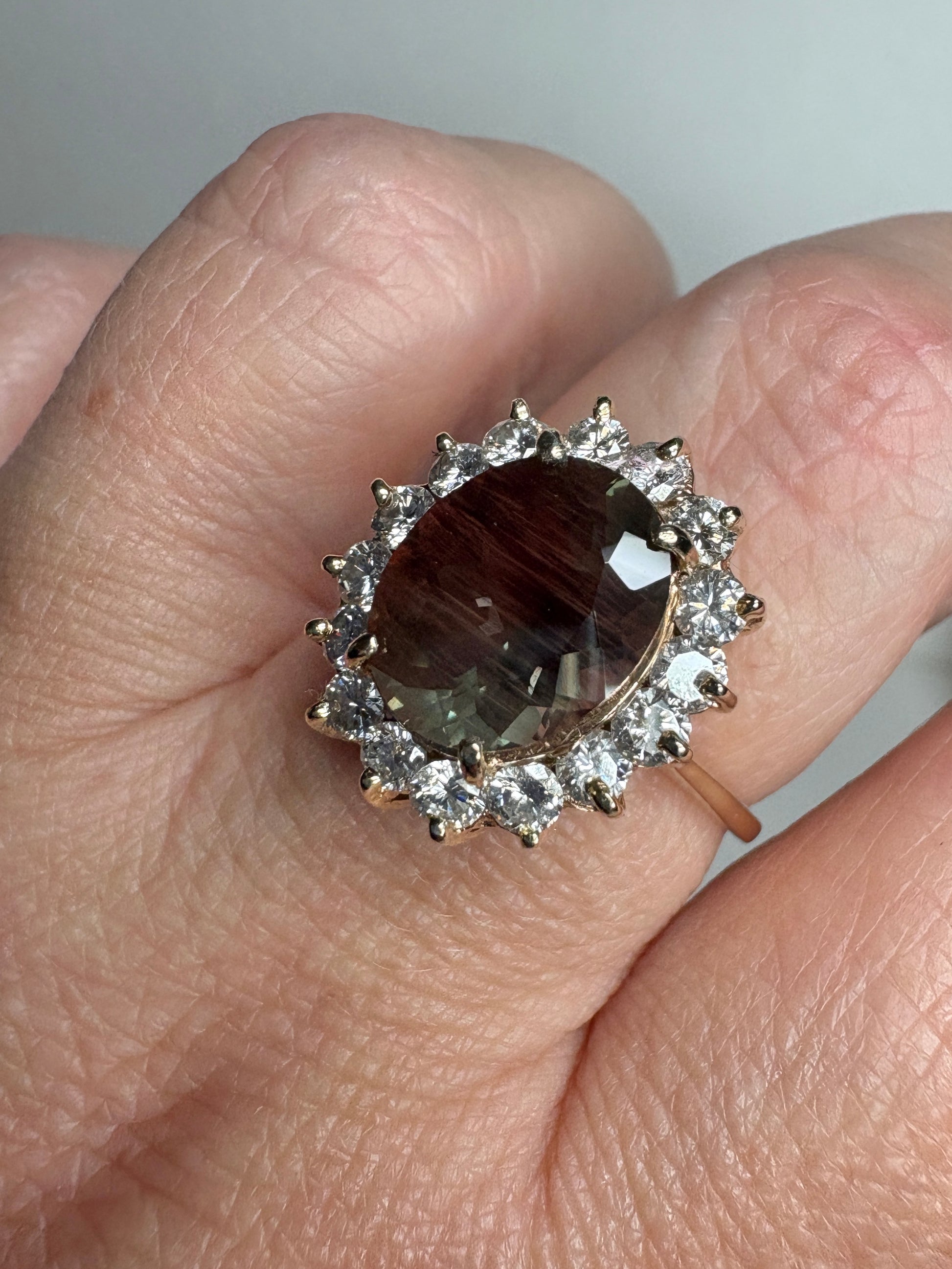 Large oval dichroic Oregon sunstone ring with diamond halo in 14k gold.