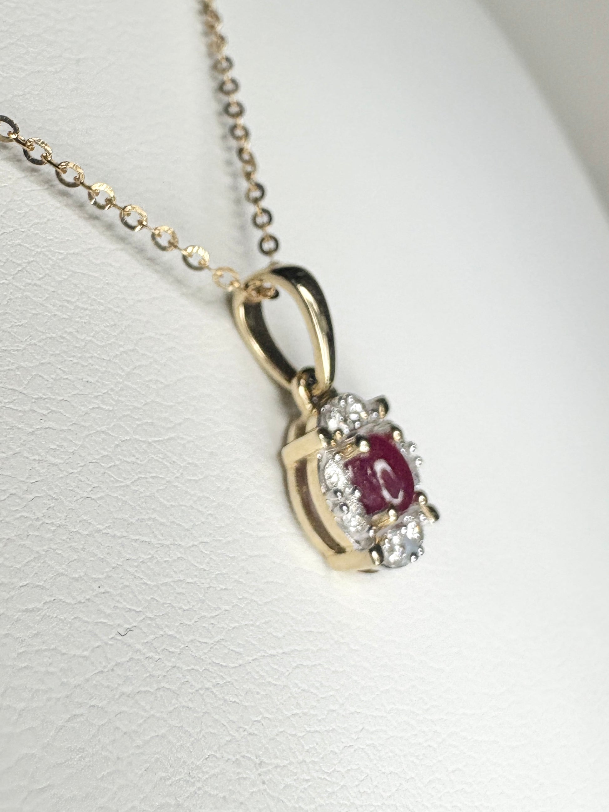 A gold pendant necklace with a ruby and diamonds on an adjustable chain.