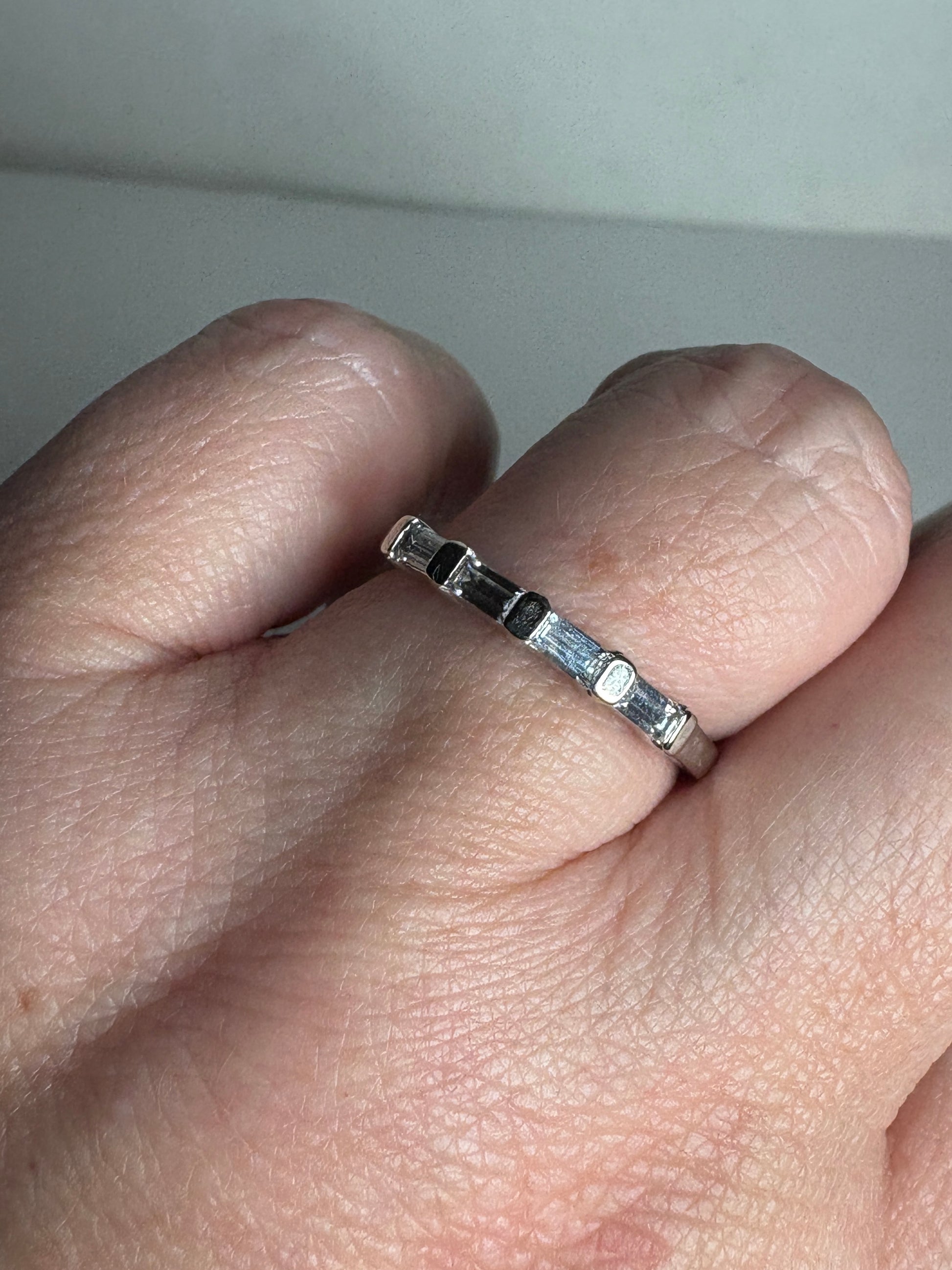 A 14k white gold band ring with baguette moissanite stones.