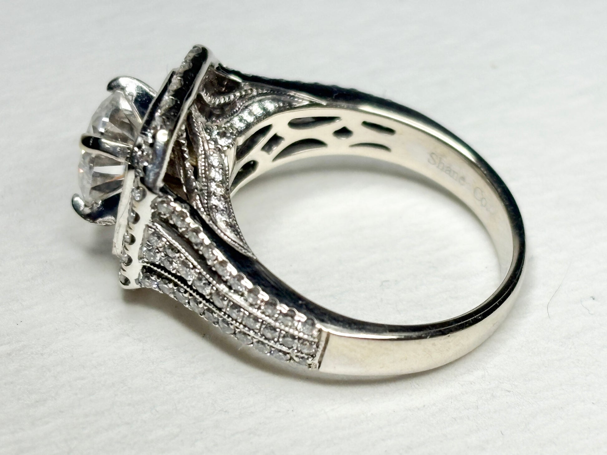 A white gold ring with a large center stone and a double halo of diamonds.