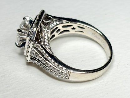 A white gold ring with a large center stone and a double halo of diamonds.