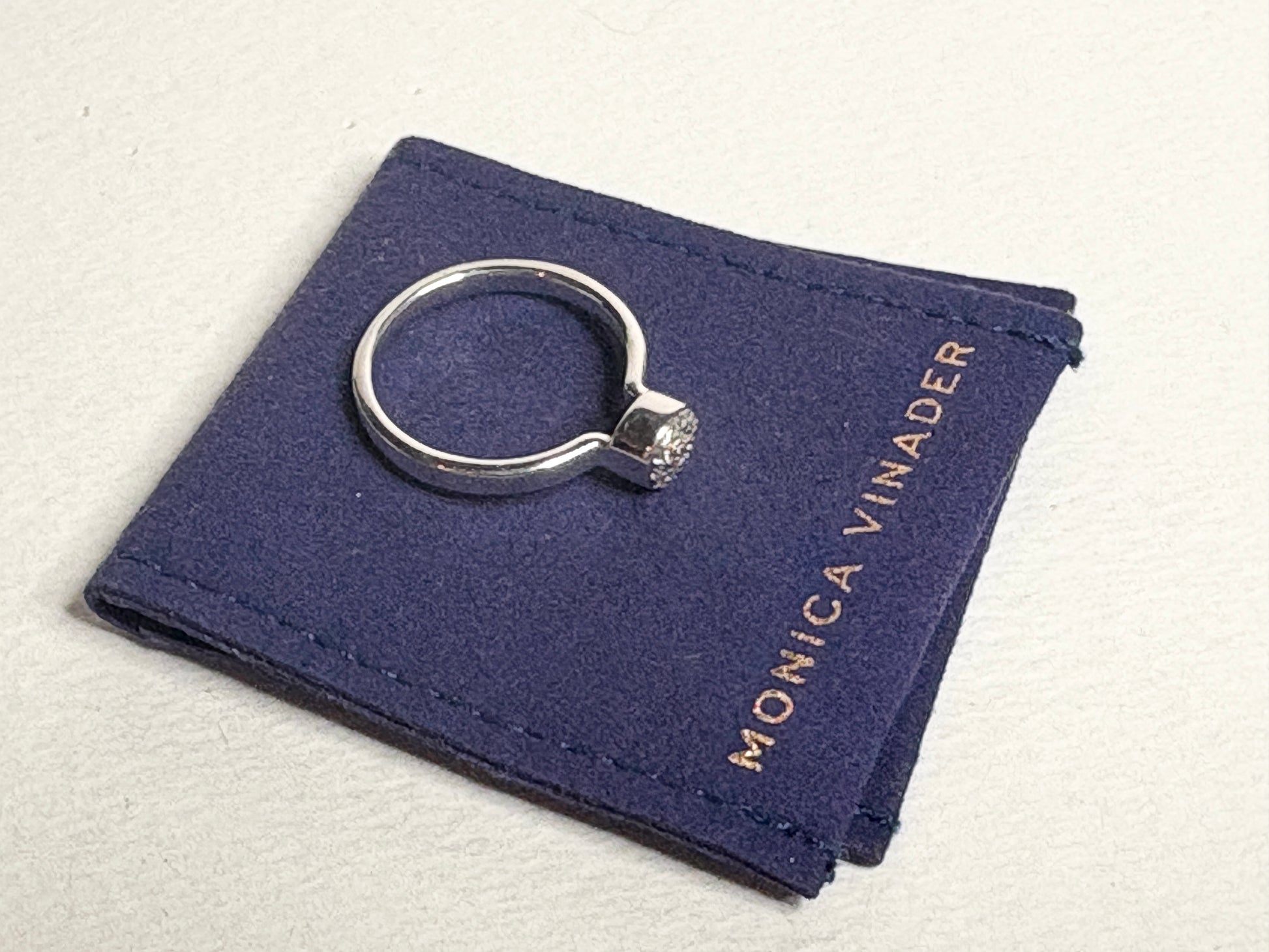 Monica Vinader sterling silver ring with pave diamonds on a blue pouch.