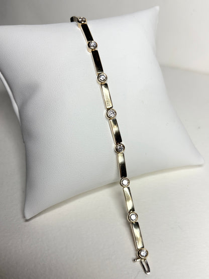 A 14k yellow gold tennis bracelet with 11 bezel-set diamonds.