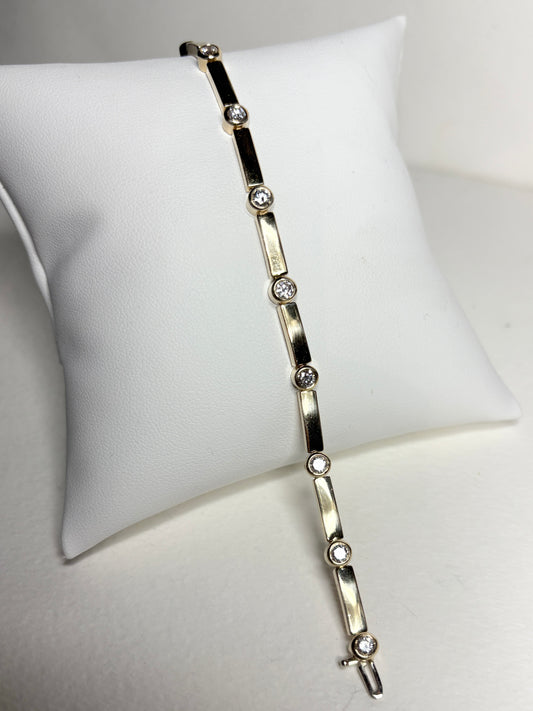A 14k yellow gold tennis bracelet with 11 bezel-set diamonds.