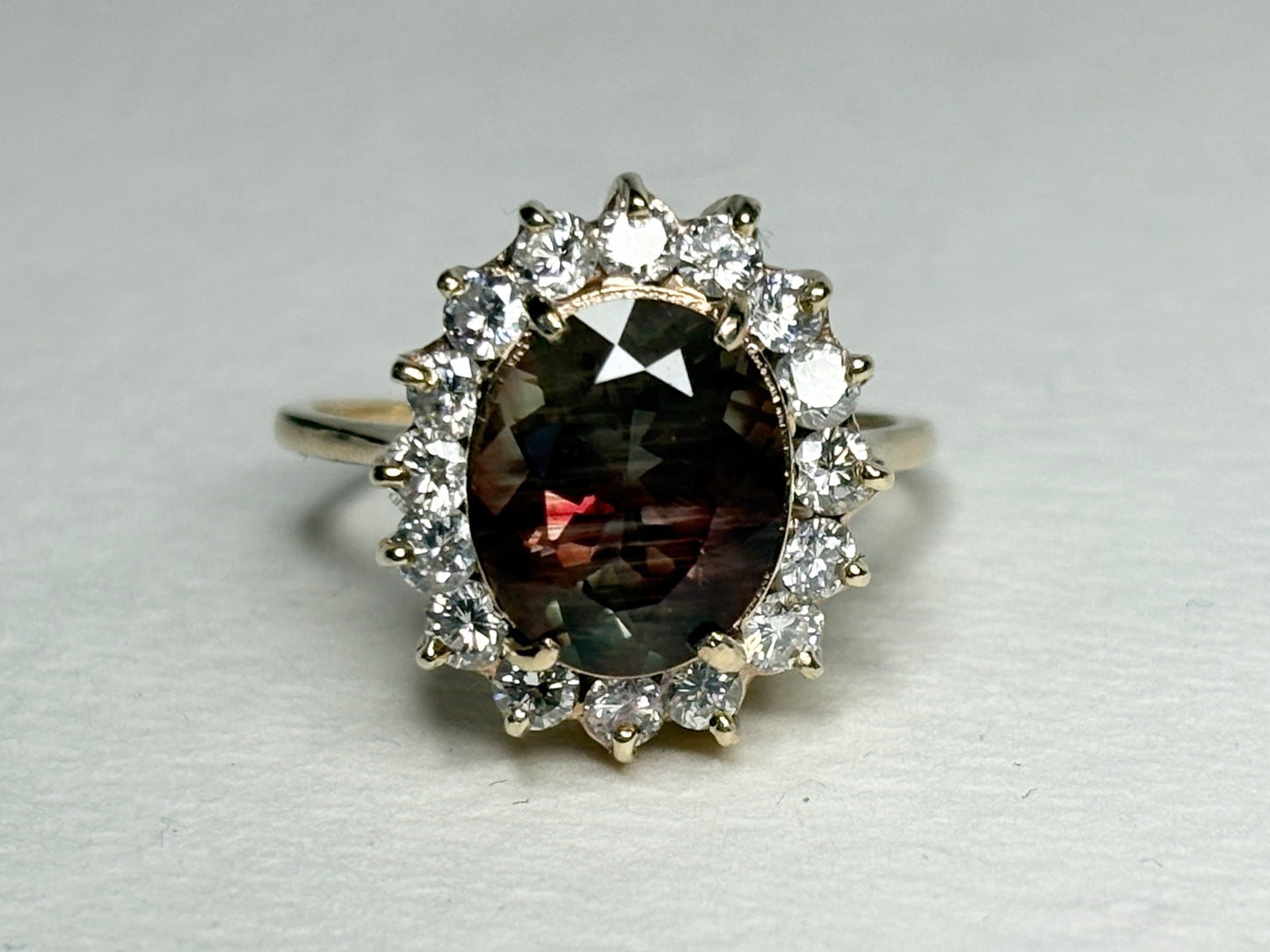 Oval dichroic Oregon sunstone ring with diamond halo in 14k gold.