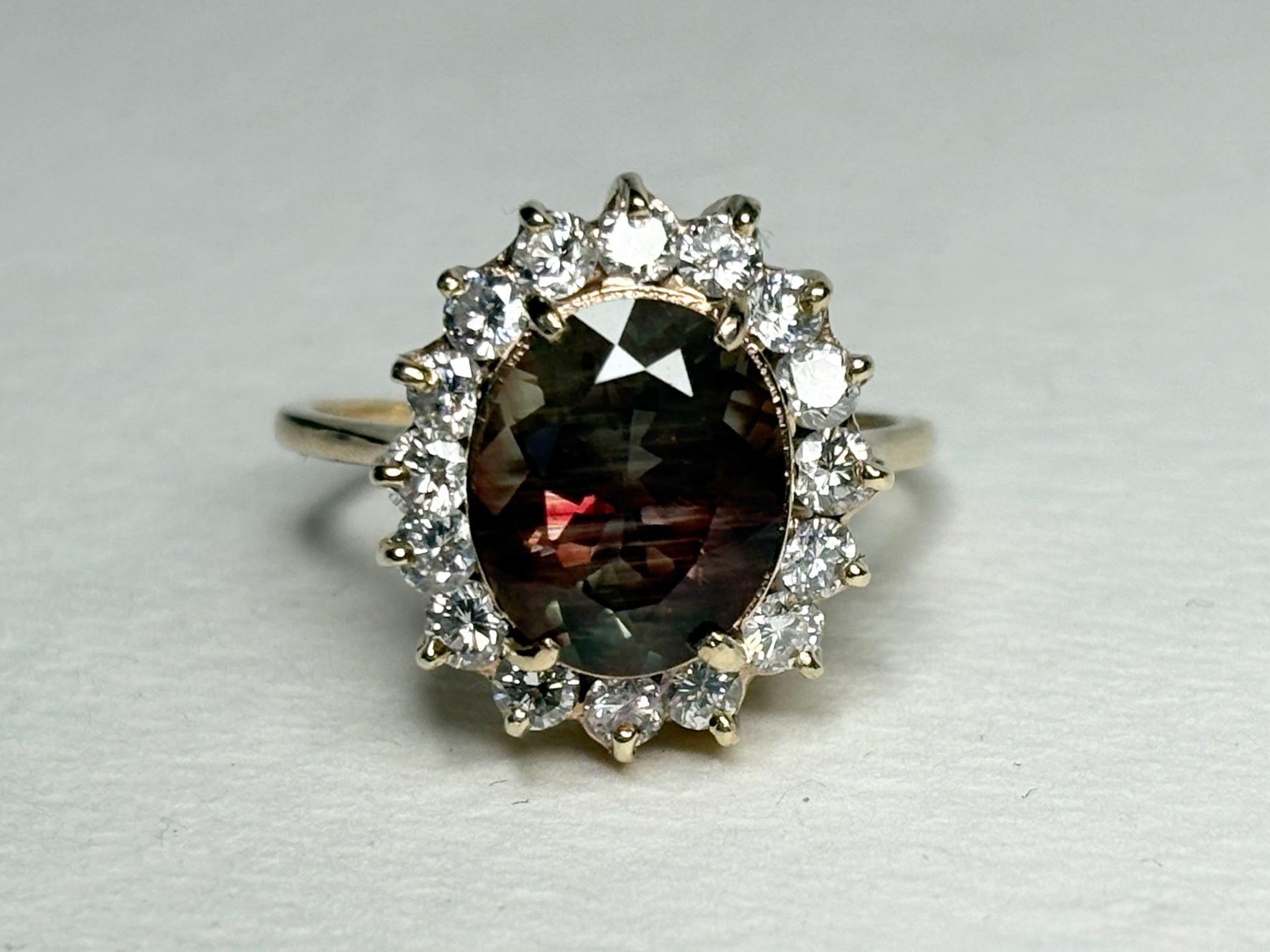Oval dichroic Oregon sunstone ring with diamond halo in 14k gold.
