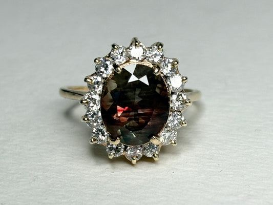 Oval dichroic Oregon sunstone ring with diamond halo in 14k gold.
