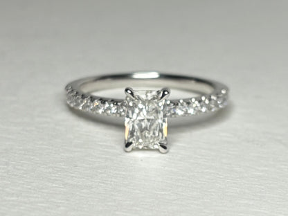 A 14k white gold engagement ring with a radiant cut diamond and pave band.